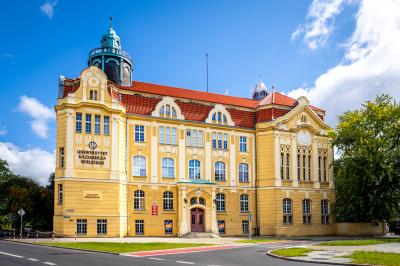Zabytkowy budynek Collegium Copernicanum, okazały gmach z wieżyczką, na fasadzie napis Uniwersytet Kazimierza Wielkiego w Bydgoszczy