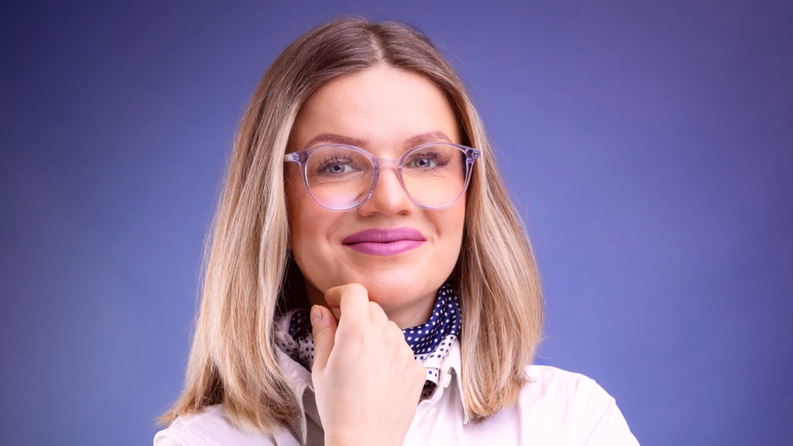 Monika Matowska, zdjęcie portretowe uśmiechniętej kobiety w okularach na granatowym tle